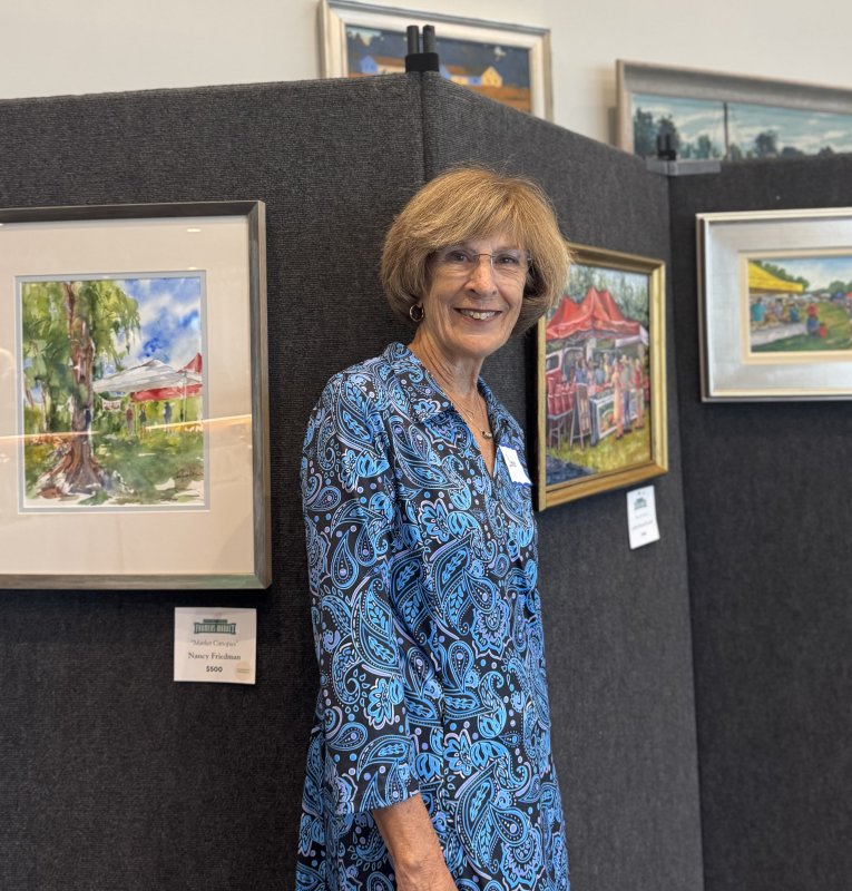 HLFM volunteer and Farmers Market Plein Air Art Exhibition Coordinator Denise Poslusny is shown with some of the artworks.